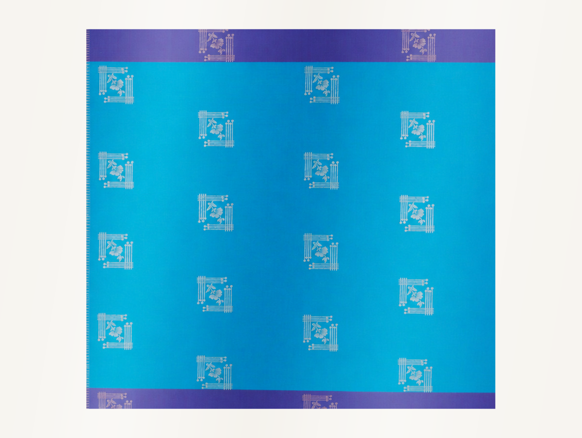 Close detail of the turquoise body fabric showing silver-toned woven floral motifs in geometric frames.